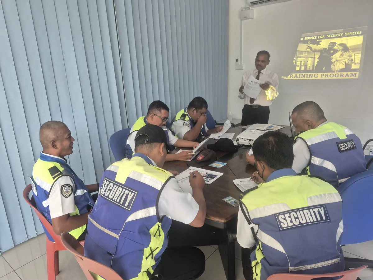 Uniformed security officers completing a classroom training exercise with an instructor at DV Intelek